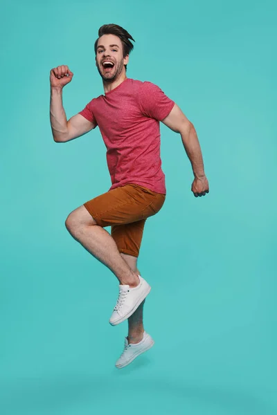 Full length of excited young man in casual clothing jumping and looking at camera — Stock Photo, Image