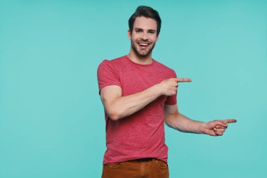 Sıradan giyinmiş yakışıklı genç adam kameraya bakıyor ve işaret ediyor.