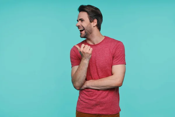 Jovem bonito em roupas casuais apontando para longe e sorrindo — Fotografia de Stock