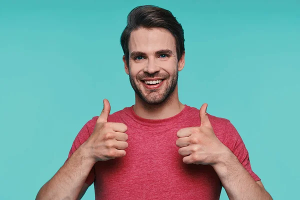 Handsome young man in casual clothing looking at camera and showing his thumbs up — Stock Photo, Image