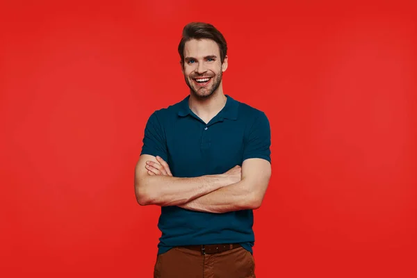 Cheerful young man in casual wear looking at camera and keeping arms crossed — Stock Photo, Image