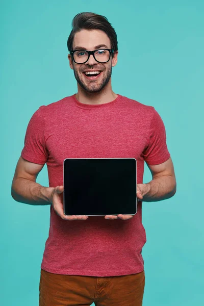 Bello giovane uomo sorridente in abbigliamento casual mostrando tablet digitale — Foto Stock