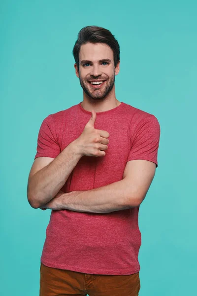 Handsome young smiling man in casual clothing looking at camera and showing his thumb up — Stock Photo, Image