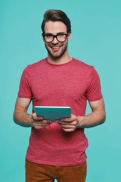 Bello giovane uomo sorridente in abbigliamento casual utilizzando tablet digitale — Foto Stock