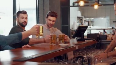 Barmen, bardaki tezgahta duran genç adamlara bira servisi yapıyor.