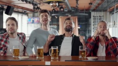 Gençlere tezahürat yapıyor, bira içiyor ve barda spor maçı seyrediyor.