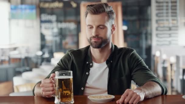 Guapo joven bebiendo cerveza mientras pasa tiempo en el pub — Vídeo de stock