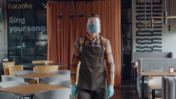 Mężczyzna kelner w ochronnej odzieży roboczej trzyma ręce skrzyżowane i patrzy w kamerę — Wideo stockowe