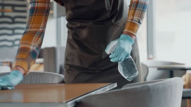 Человек в защитных перчатках чистит стол для клиентов — стоковое видео
