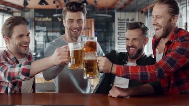 Heureux les jeunes hommes en vêtements décontractés trinquer les uns les autres avec de la bière le pub — Video