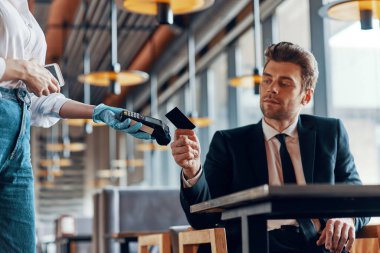 Yakışıklı, takım elbiseli genç adam restoranda otururken kesintisiz ödeme yapıyor.