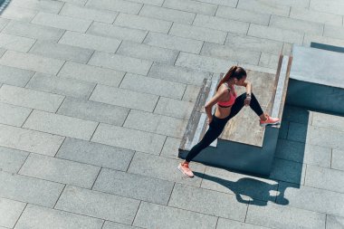 Kendine güvenen genç bir kadının spor giyim kuşamında açık havada egzersiz yaptığı en iyi manzara.