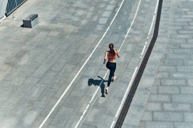 Açık havada koşan spor elbiseli genç bir kadın manzarası.
