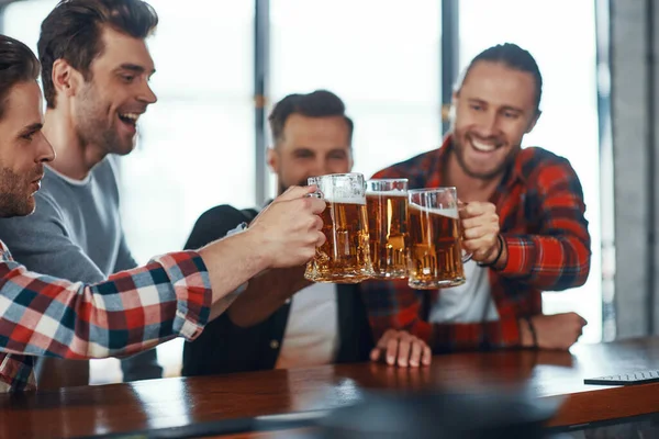 Gelukkig jonge mannen in casual kleding toosten elkaar met bier en glimlachen — Stockfoto