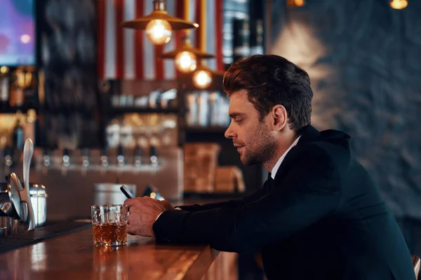 Side view of handsome young man in full suit using smart phone — Stock Photo, Image