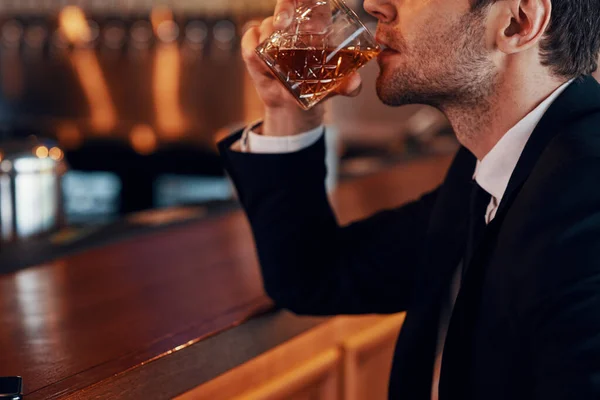 Nahaufnahme eines jungen Mannes im Anzug, der Whisky trinkt, während er im Restaurant an der Theke sitzt — Stockfoto