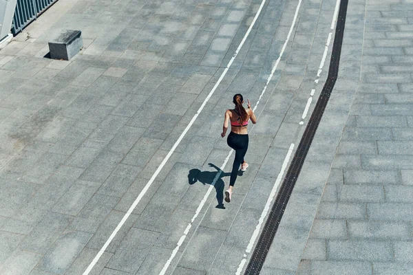 Vista superior de la mujer joven en ropa deportiva corriendo al aire libre —  Fotos de Stock