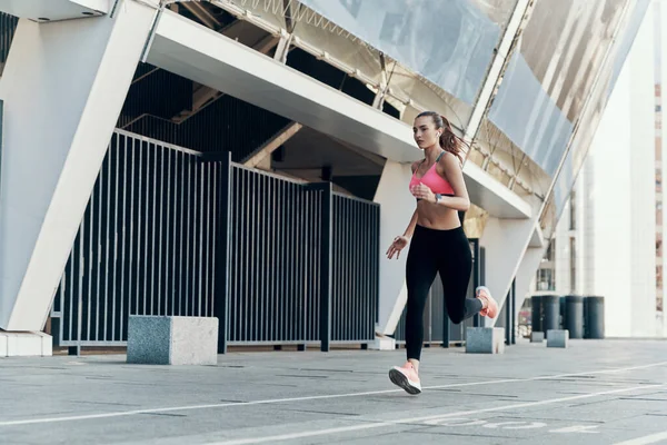 Полная длина уверенной молодой женщины в спортивной одежде, бегущей на открытом воздухе — стоковое фото