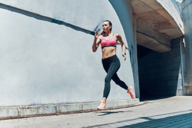 Açık havada koşan spor elbiseli güzel bir kadın.