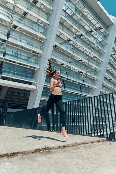 Jovem confiante em roupas esportivas correndo ao ar livre — Fotografia de Stock