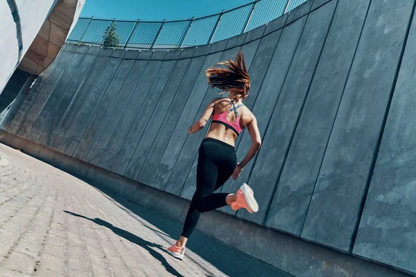 Vista posteriore della giovane donna in abbigliamento sportivo che corre all'aperto — Foto Stock