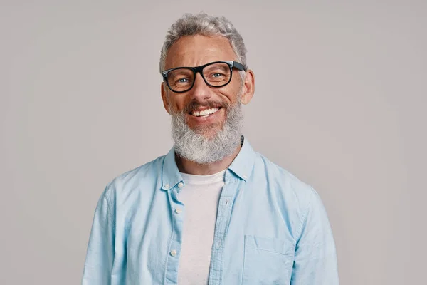 Bonito homem sênior de óculos olhando para a câmera e sorrindo — Fotografia de Stock