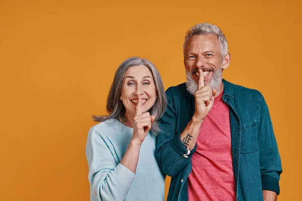 Mooi senior paar kijken naar camera en houden vinger op de lippen — Stockfoto