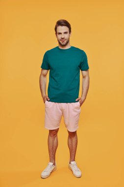 Uzun boylu, rahat giyimli yakışıklı bir adam kameraya bakıyor.