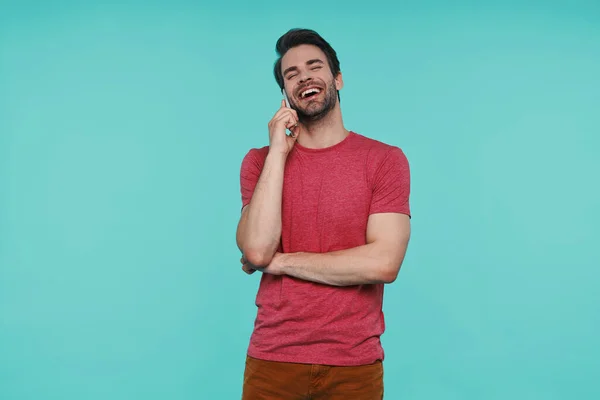 Bonito jovem sorridente homem em roupas casuais falando no telefone inteligente — Fotografia de Stock