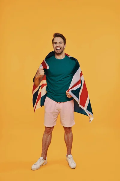 Full length of handsome young man in casual clothing carrying British flag
