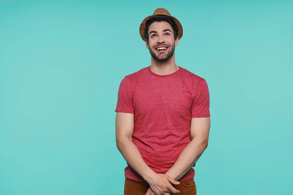 Hezký mladý muž v klobouku fedora vzhlíží a usmívá se, zatímco stojí na modrém pozadí — Stock fotografie