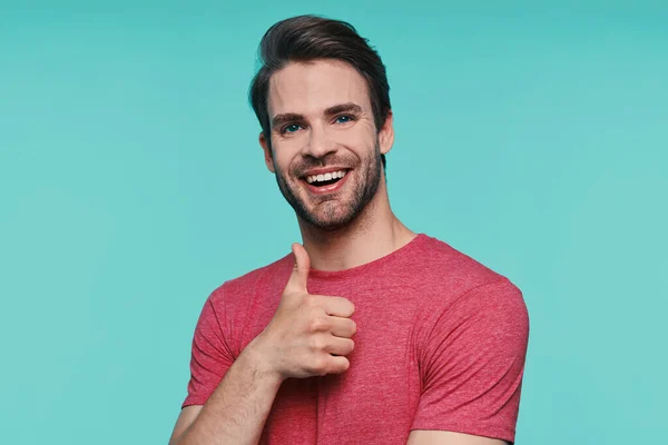 Handsome young man in casual clothing looking at camera and showing his thumb up — Stock Photo, Image
