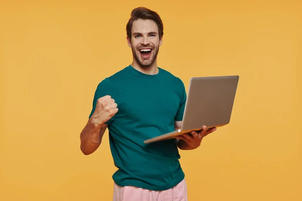 Stilig ung leende man i casual kläder bär laptop och gester — Stockfoto