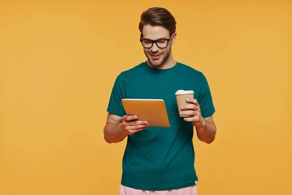 Handsome young man in casual clothing carrying digital tablet and cup — Stock Photo, Image