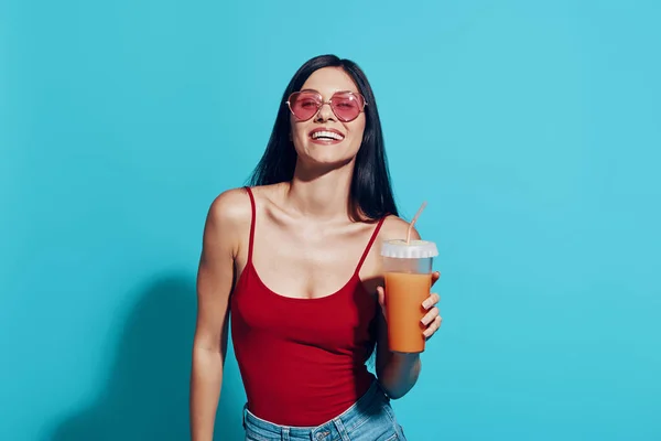 Attraente giovane donna in possesso di tazza con bevanda rinfrescante e sorridente — Foto Stock