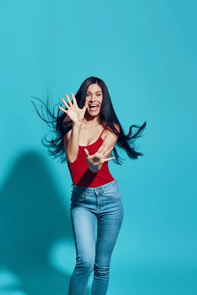 Attraktive junge Frau blickt in die Kamera und lächelt vor blauem Hintergrund — Stockfoto