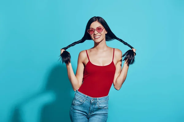 Attraente giovane donna che si tocca i capelli e sorride in piedi sullo sfondo blu — Foto Stock