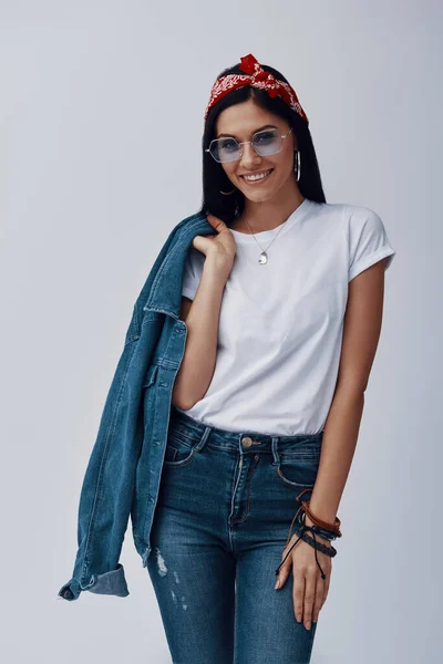 Attractive young woman in bandana carrying denim shirt on shoulder and smiling — 图库照片