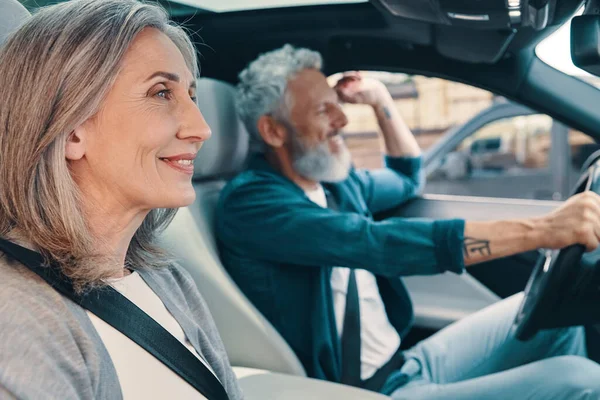 Heureux couple de personnes âgées appréciant la promenade en voiture tout en étant assis sur les sièges avant de la voiture — Photo