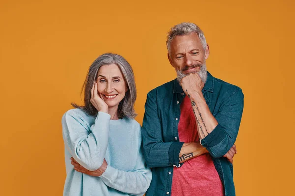 Vackra senior par ler när de står tillsammans mot orange bakgrund — Stockfoto