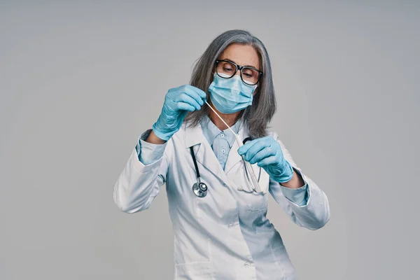 Rijpere mooie vrouwelijke arts in het gezicht masker houden medische test — Stockfoto