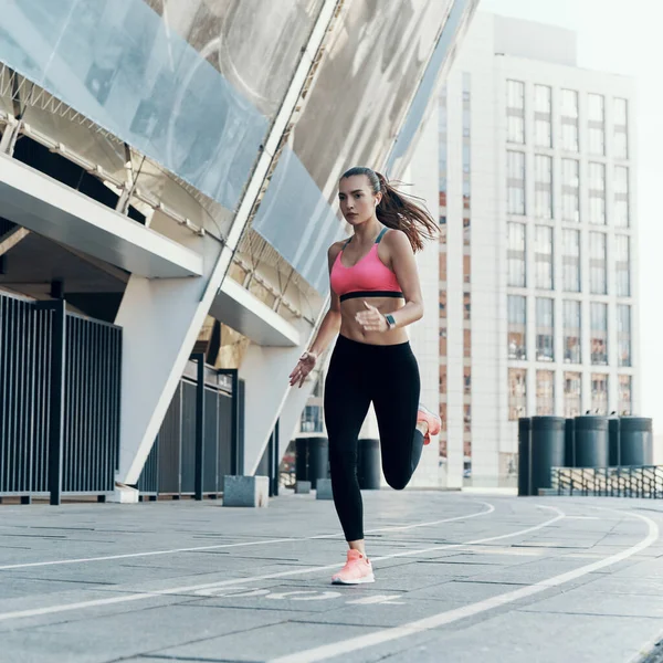 Πλήρες μήκος της όμορφης νεαρής γυναίκας με αθλητικά ρούχα που τρέχουν σε εξωτερικούς χώρους — Φωτογραφία Αρχείου