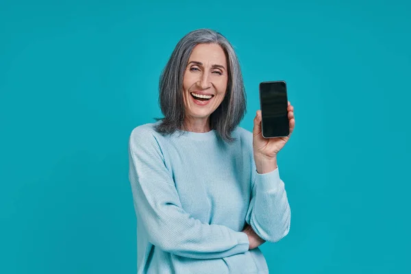 Madura hermosa mujer mostrando su teléfono inteligente y sonriendo — Foto de Stock