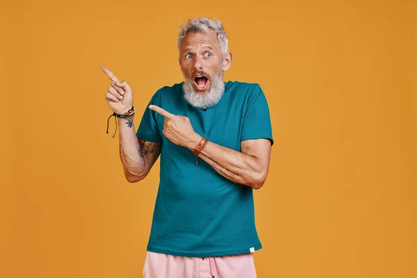 Surprised senior man pointing copy space and making a face — Stock Photo, Image