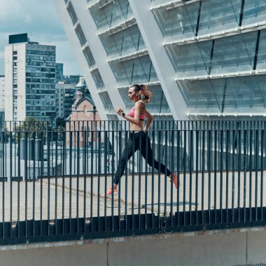 Açık havada koşan spor elbiseli güzel bir genç kadın.
