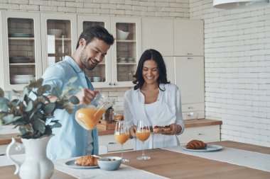 Genç ve mutlu bir çift birlikte kahvaltı hazırlarken evdeki mutfakta vakit geçiriyorlar.