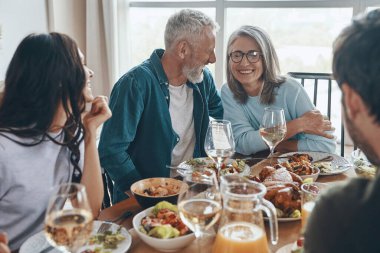Mutlu çoklu nesil aile yemeği yerken iletişim kuruyor ve gülümsüyor.