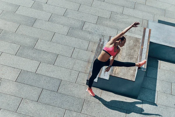 Vista superior de la mujer joven y confiada en ropa deportiva que hace ejercicio al aire libre —  Fotos de Stock