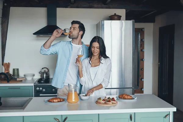 Gyönyörű fiatal pár reggelit készít, miközben a konyhában töltik az idejüket — Stock Fotó
