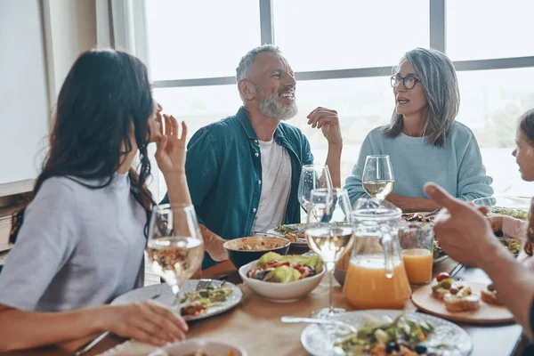 Feliz familia multi-generación comunicándose y sonriendo mientras cenan juntos —  Fotos de Stock